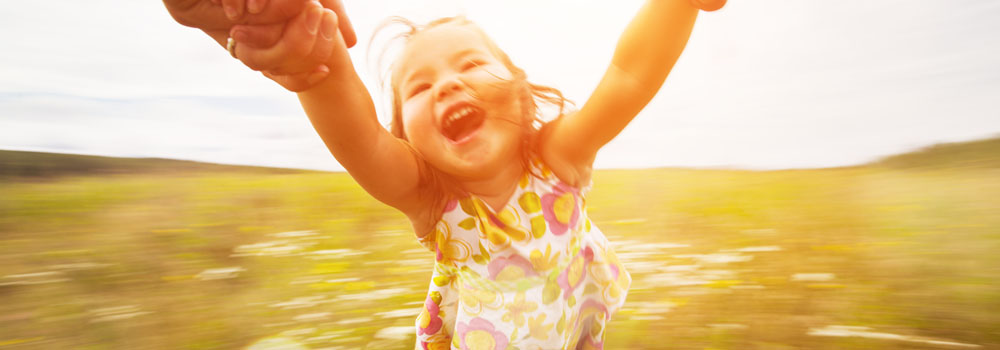 An adult spins a child around in a field