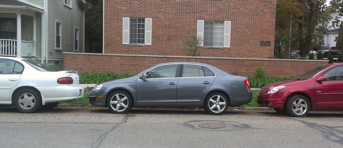 Three cars closely parked on the street