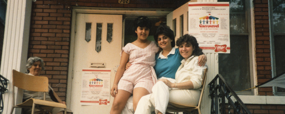 Historical photo of Armenian community members on the porch of the former Armenian Community Centre decorated with posters for the Carrousel of the Nations
