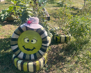 South Merritt Community Garden Clickable thumbnail, image of a painted smiley face on a tire that outlines a whole community garden