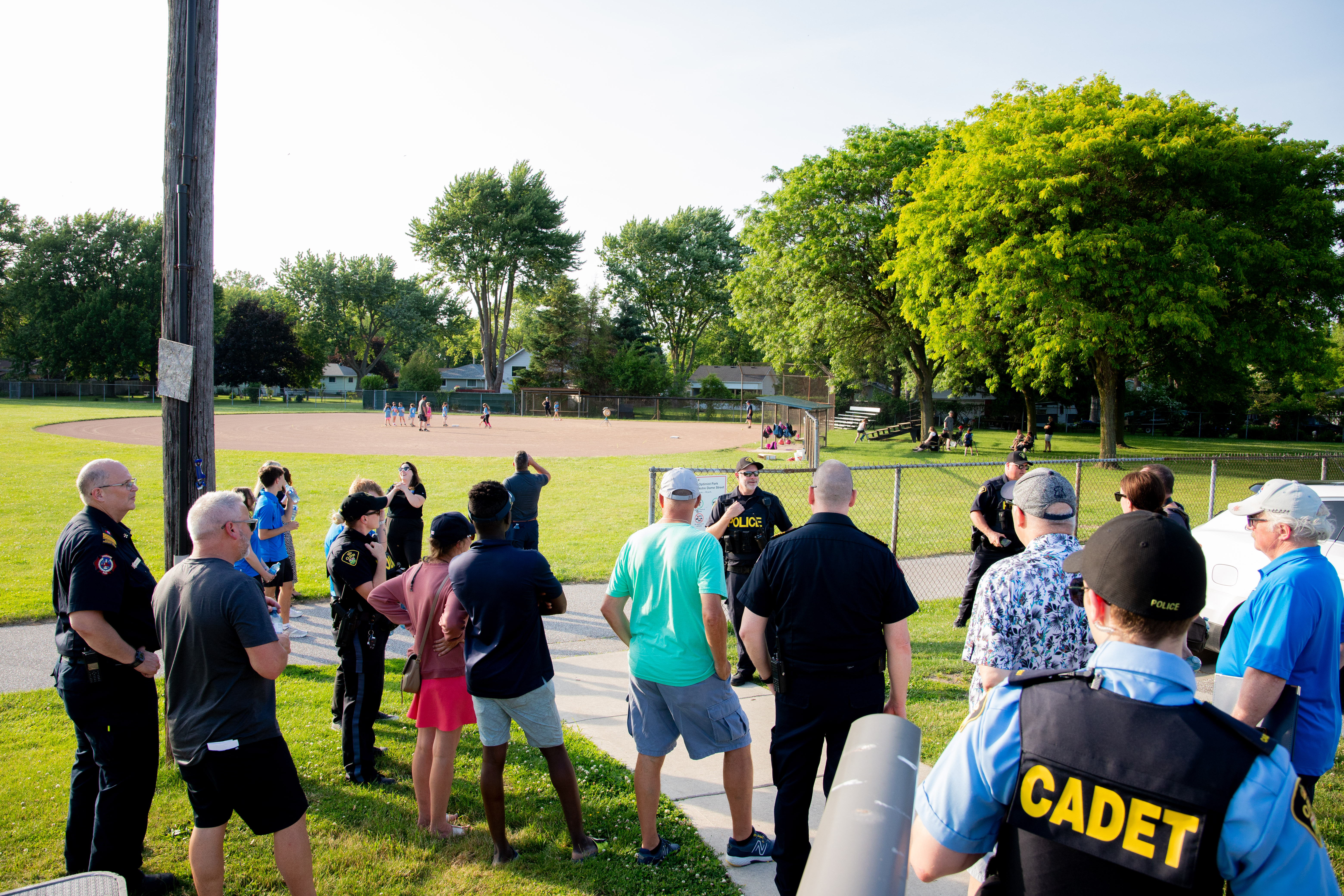 A group of residents and police officers gathered outside at a park