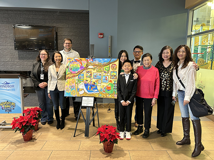 Artist and attendees of unveiling ceremony standing with artwork